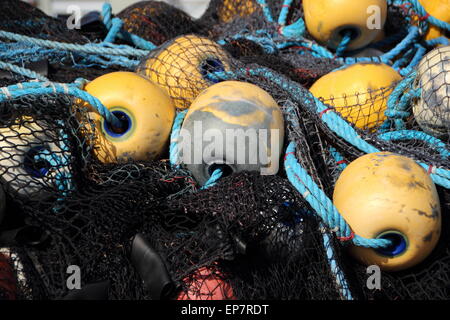 Closeup on Black Fishing Net Pile with Yellow Float in Background Stock Photo