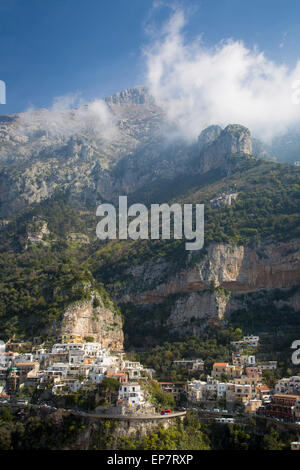 Massive mountains dwarf the town of Positano along the Amalfi Coast, Campania, Italy Stock Photo