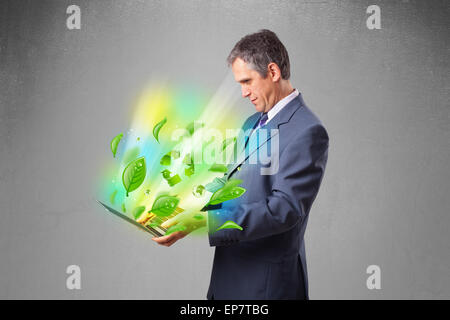 Businessman holding laptop with recycle and environmental symbols Stock Photo