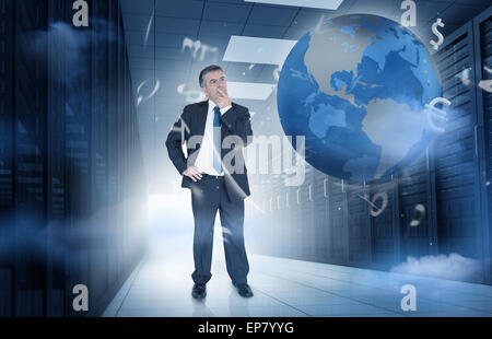 Businessman standing in data center with currency graphics and earth Stock Photo