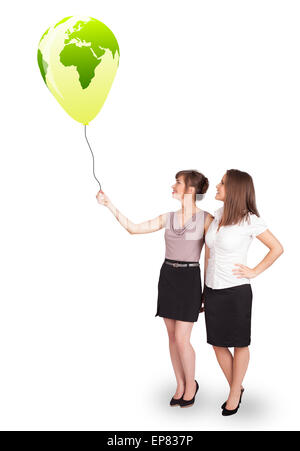 Happy ladies holding a green globe balloon Stock Photo