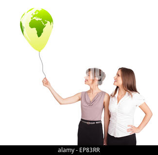 Happy ladies holding a green globe balloon Stock Photo