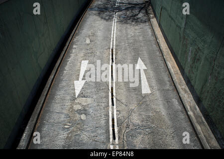 white arrows painted on a road in either direction viewed from above Stock Photo