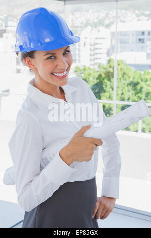Smiling architect holding plans and wearing hardhat Stock Photo