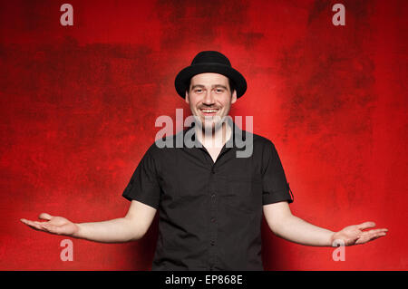 Young man posing, raising his hand on a red background. Stock Photo