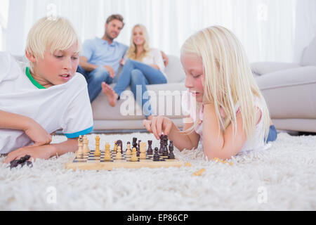 Parents looking at their children playing chess Stock Photo