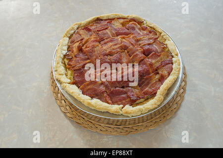 home made bacon lattice top mashed potato pie sitting on table on a wicker hot pad Stock Photo