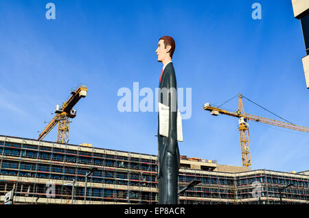 Statue of 'The Tall Banker' in Kirchberg, Luxembourg City, and construction cranes in the background