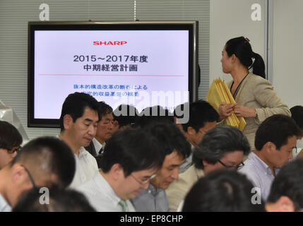 Tokyo, Japan. 14th May, 2015. A staff member o financially struggling Sharp Corp. distributes papers to members of the media before a news conference by its President Kozo Takahashi at its Tokyo head office on Thursday, May 14, 2015. Takahashi said the loss-making electronics maker will sell its head office in Osaka, western Japan, cut around 3,400 jobs in Japan, reduce salaries and bonuses for workers, and withdraw from unprofitable areas. © Natsuki Sakai/AFLO/Alamy Live News Stock Photo