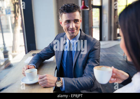 Happy couple sitting at the table near window and drinking coffee in cafe Stock Photo