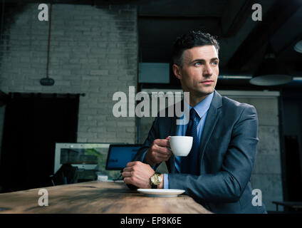 Pensive businessman drinking coffee in cafe and looking away Stock Photo
