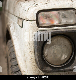 Muddy white jeep covered in dried mud and headlamp Stock Photo