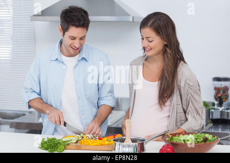 Man chopping mushrooms next to his pregnant partner Stock Photo