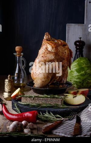 Roasted whole chicken with apples, spices and herbs on a wooden table. Tasty food. Rustic style. Stock Photo