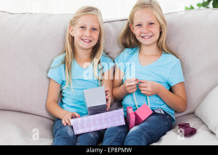 Cute twins unwrapping birthday gift sitting on a couch Stock Photo