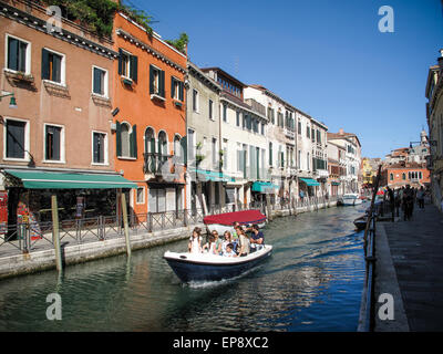 A group of tourists taking a pleasure trip in a motor boat along one of Venice's canals Stock Photo