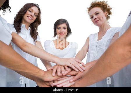 Cheerful models joining hands in a circle and looking at camera Stock Photo