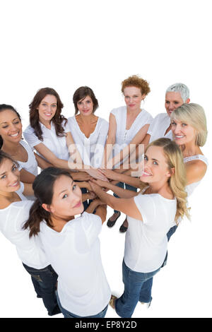 Happy female models joining hands in a circle and looking at camera Stock Photo