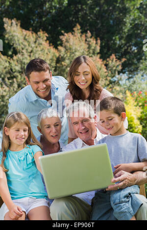 Multi generation family with a laptop sitting in park Stock Photo