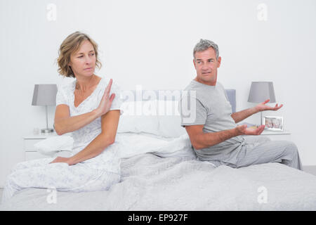 Couple sitting on different sides of bed having an argument Stock Photo