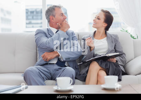 Colleagues working together sitting on sofa having coffee Stock Photo