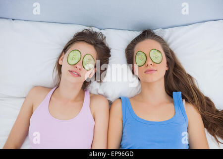 Friends relaxing in bed with cucumber on eyes Stock Photo