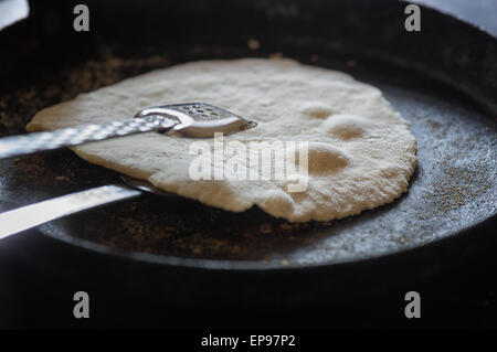Floury tortillas being turned while cooking in hot griddle pan. Stock Photo