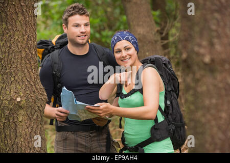 Fit couple reading map in a forest with woman pointing Stock Photo