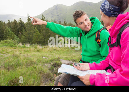 Couple sitting on a rock during hike using compass and map Stock Photo