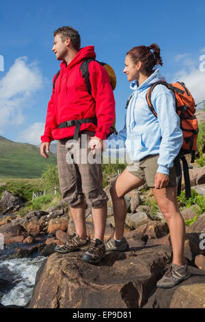 Couple standing at edge of river on a hike holding hands Stock Photo