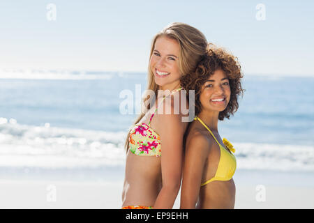 Smiling friends in bikinis standing back to back Stock Photo