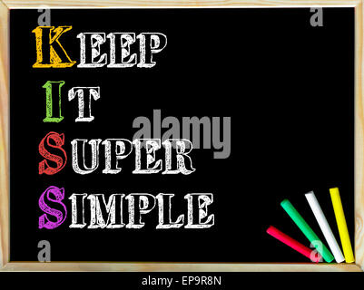 Acronym KISS as KEEP IT SUPER SIMPLE. Written note on wooden frame blackboard, colored chalk in the corner. Motivational Concept image Stock Photo