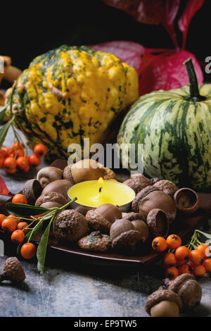 Pumpkins, nuts, berries and mushrooms chanterelle with burning candle Stock Photo