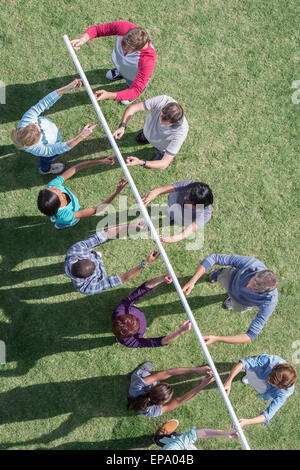 team holding pole fingertip Stock Photo