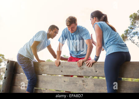 helping man wall boot camp obstacle course Stock Photo