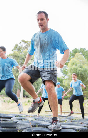 man jumping tire boot camp obstacle course Stock Photo