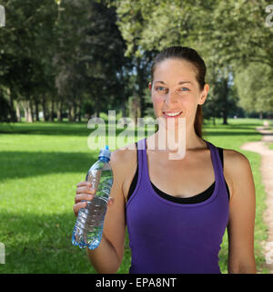 Sportliche Frau mit Wasserflasche beim Joggen oder Laufen Stock Photo
