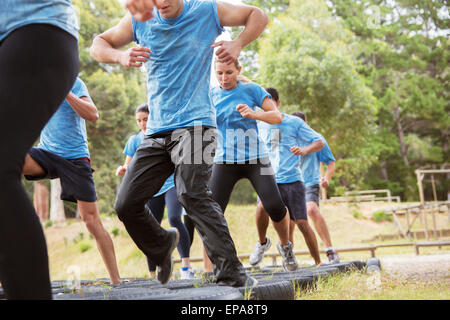 people jumping tire boot camp obstacle course Stock Photo