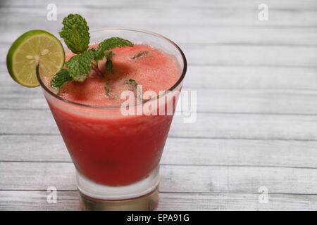 Watermelon and lime juice in a clear glass, on rustic wooden board Stock Photo