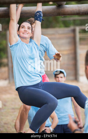 smiling woman crossing monkey bars boot camp Stock Photo