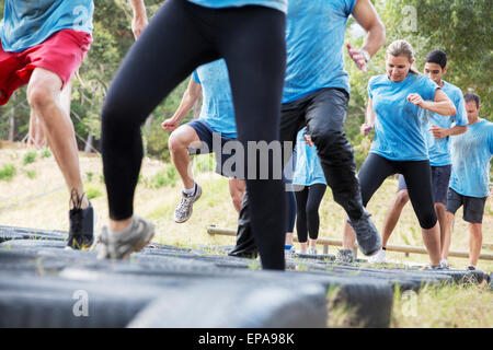 people jumping tire boot camp obstacle course Stock Photo