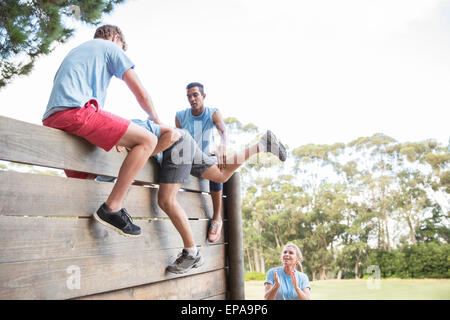 helping man wall boot camp obstacle course Stock Photo