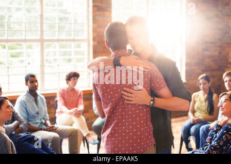 man hugging group therapy session Stock Photo
