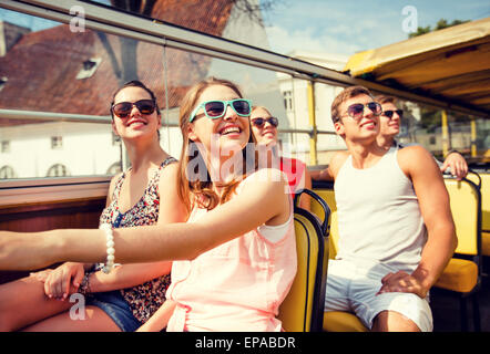 group of smiling friends traveling by tour bus Stock Photo