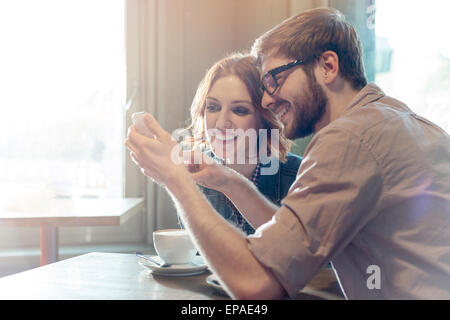 heterosexual couple using cell phone cafe Stock Photo