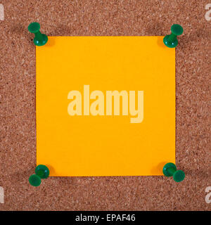 Blank orange note paper pinned to a noticeboard. Stock Photo