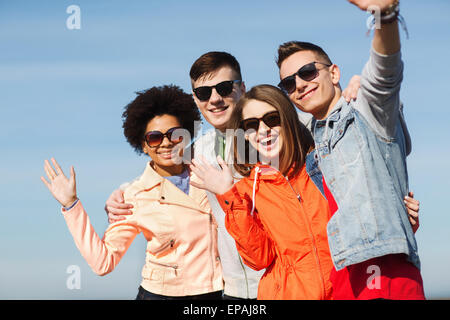 happy teenage friends in shades waving hands Stock Photo