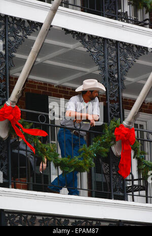 Man with cowboy hat and jeans looks over Bourbon Street, Four Points by Sheraton hotel balcony amongst holiday decorations Stock Photo