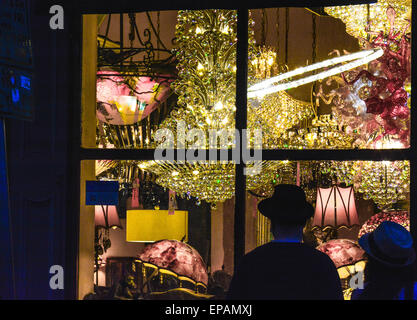 Window shoppers enjoy the night view of a chandelier lighting store display in the French Quarter in New Orleans, LA Stock Photo