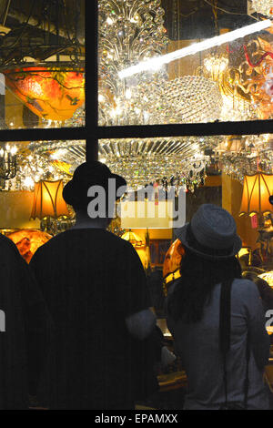 Window shoppers enjoy the night view of a chandelier lighting store display in the French Quarter in New Orleans, LA Stock Photo